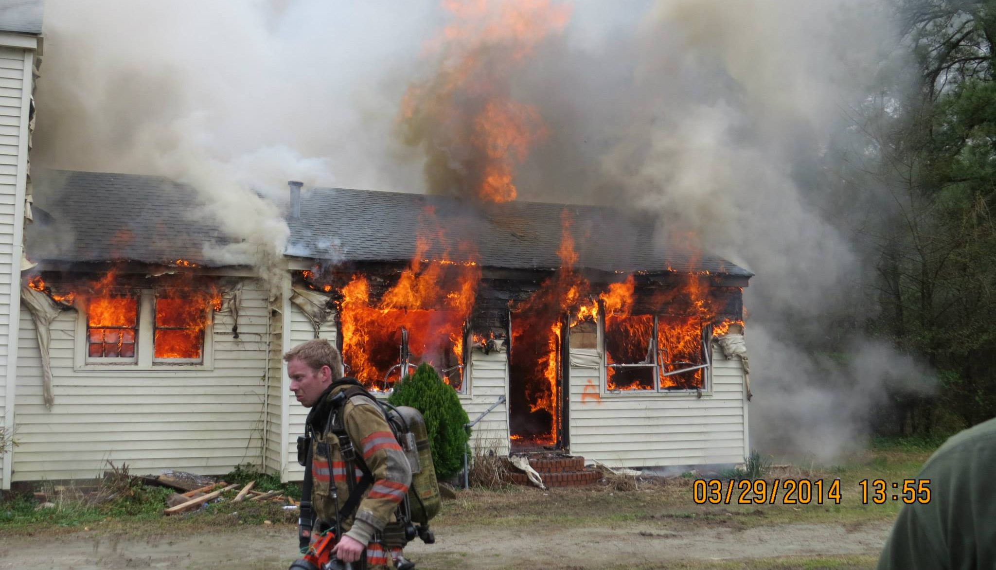 Fireman walking past burning building.